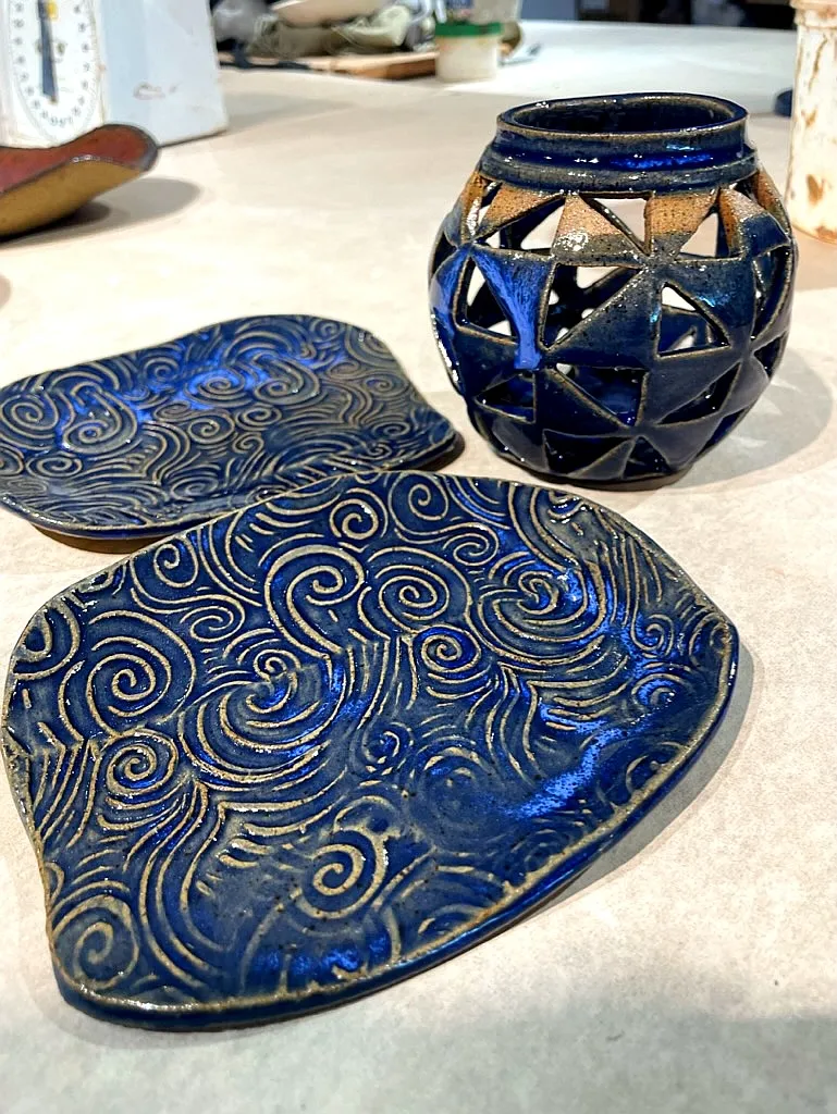 Two carved blue spoon rests and a pierced blue lantern on the studio table