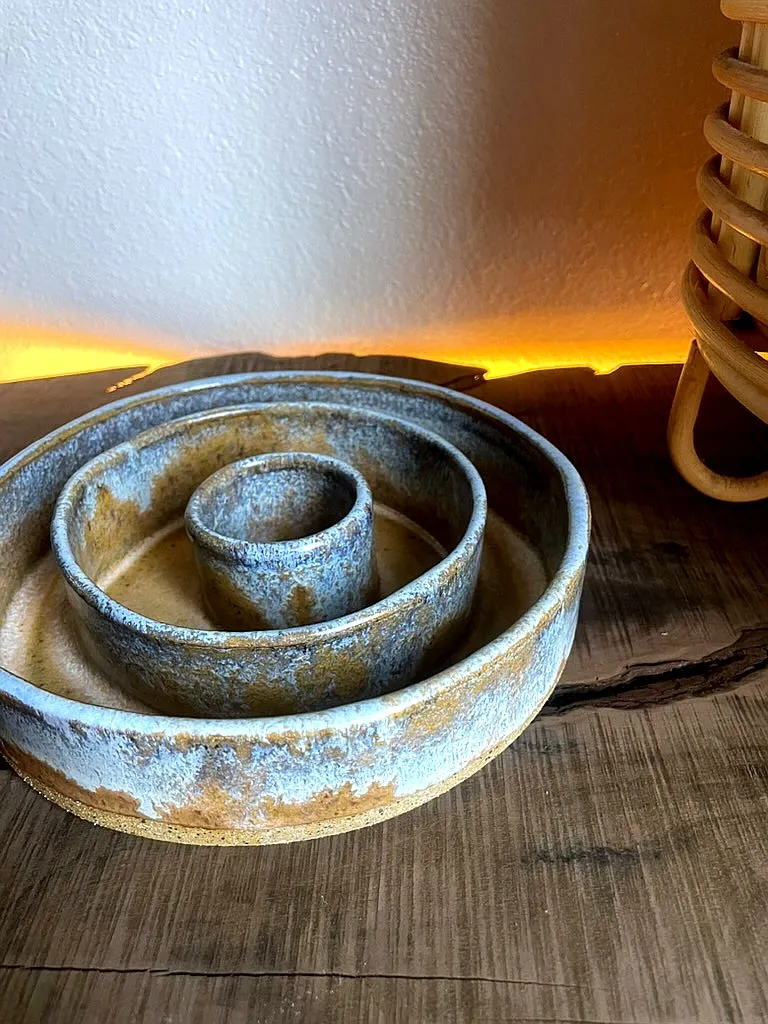 A tiered slow-feeder dog bowl in a tan glaze