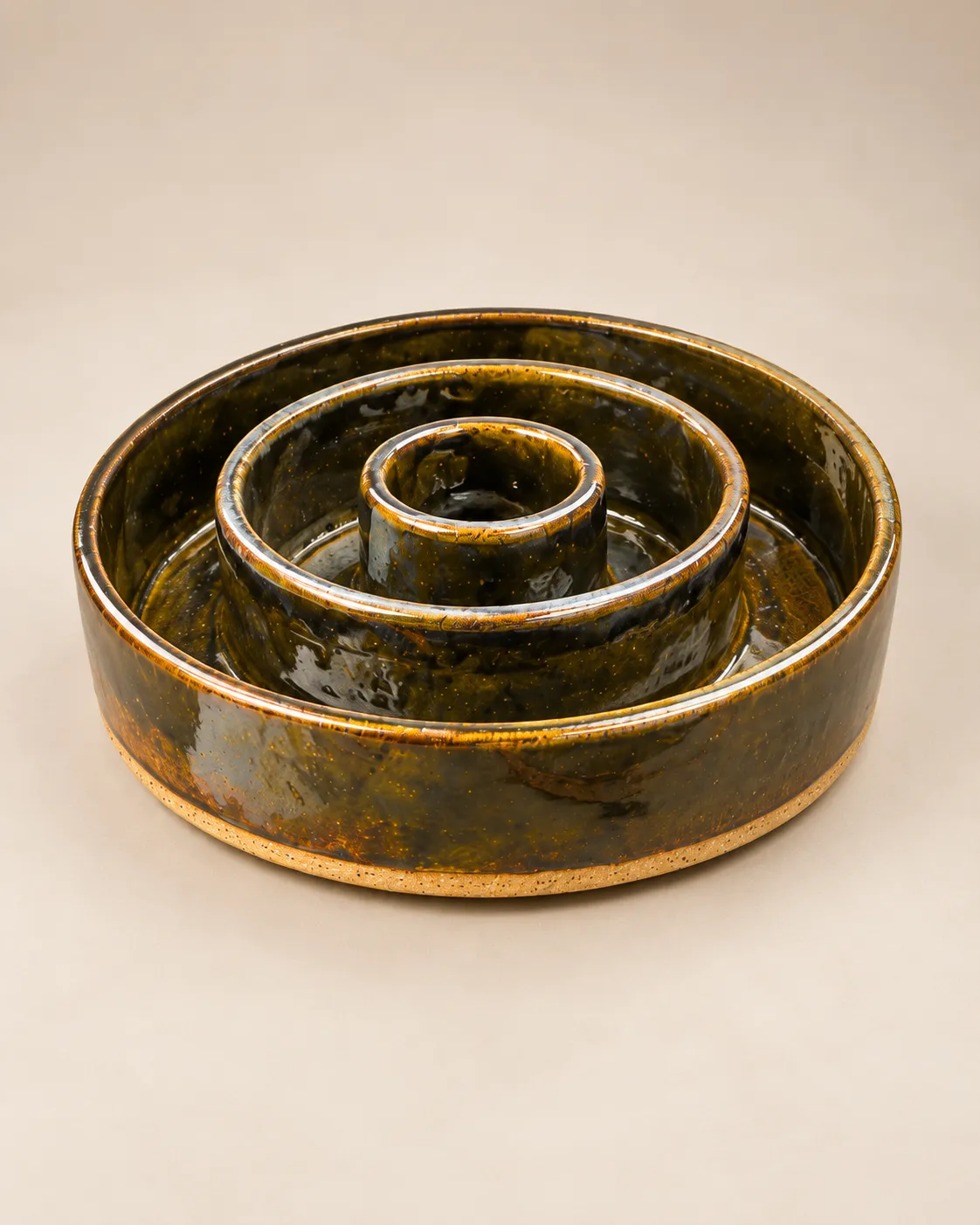 Ringed slow-feeder dog bowl in glossy dark brown glaze with raw clay foot