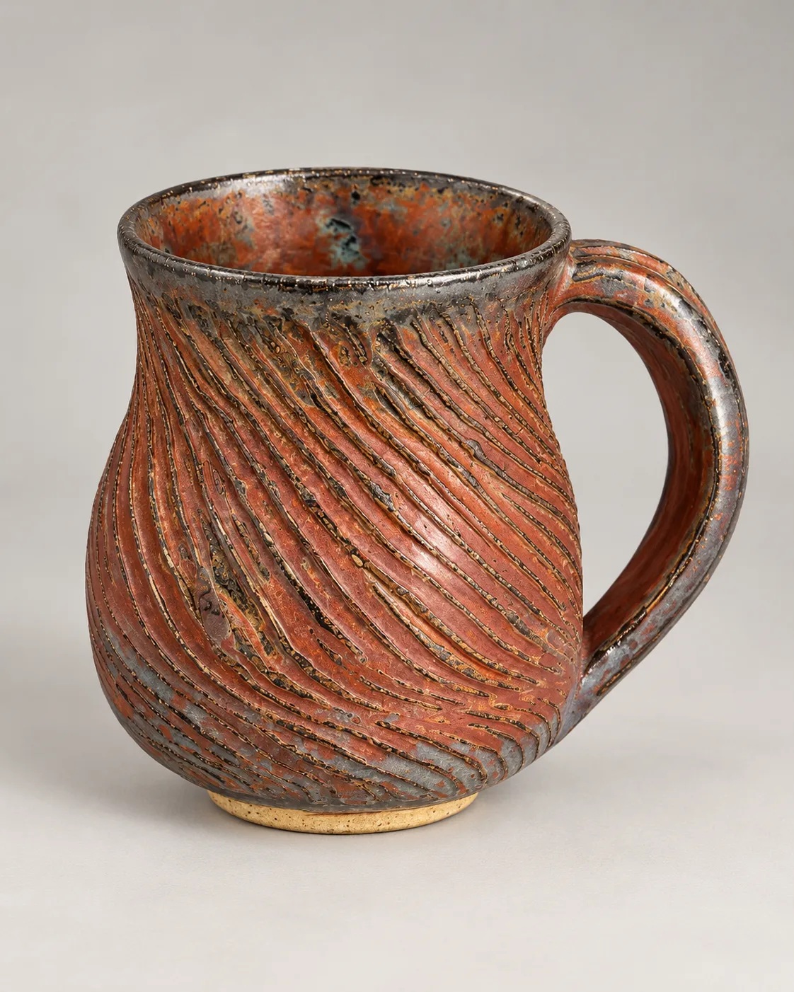 Bellied mug with diagonal carved ridges in copper-red metallic glaze, gunmetal rim and handle