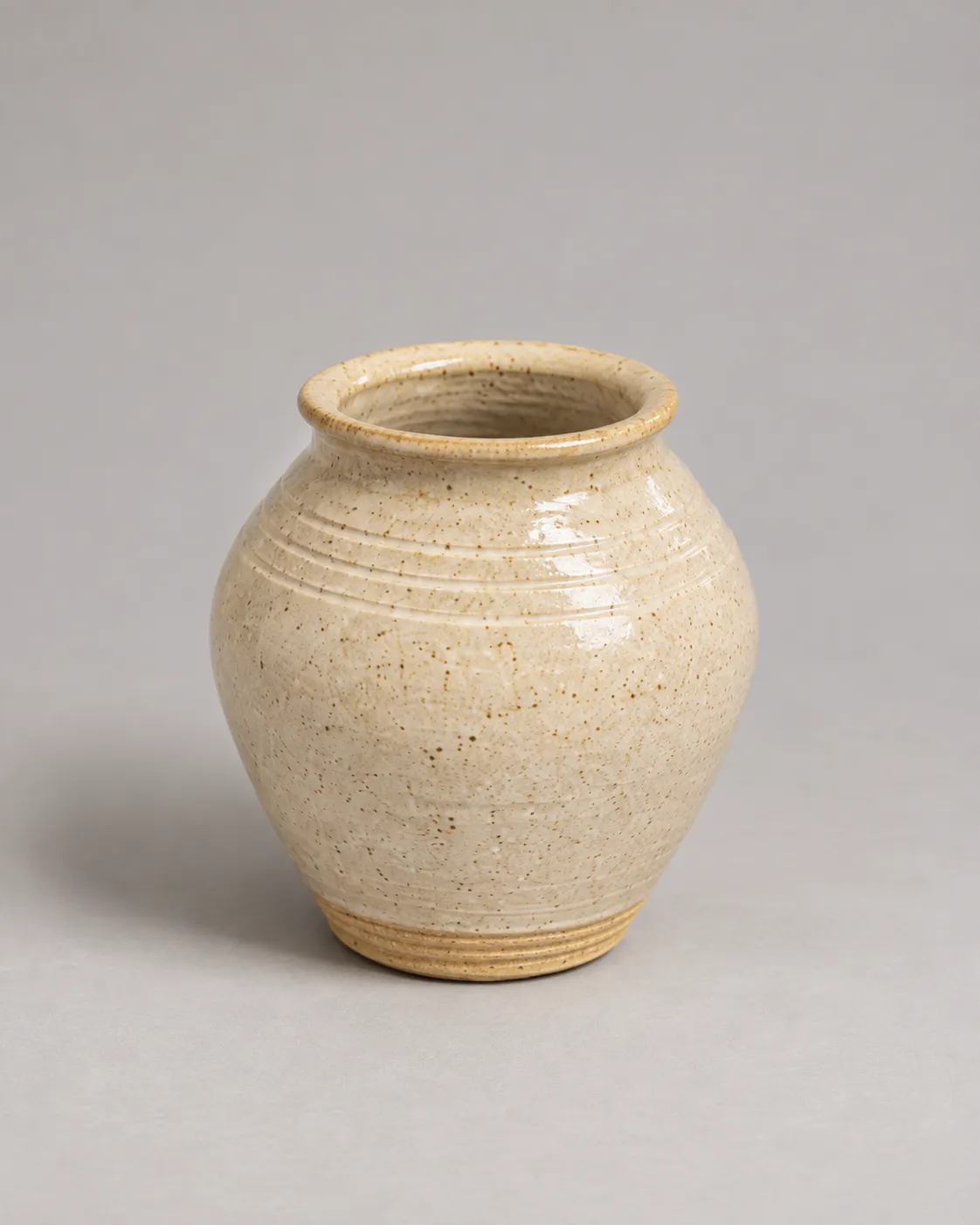 Speckled cream vase with throwing rings at the shoulder and an exposed ridged foot