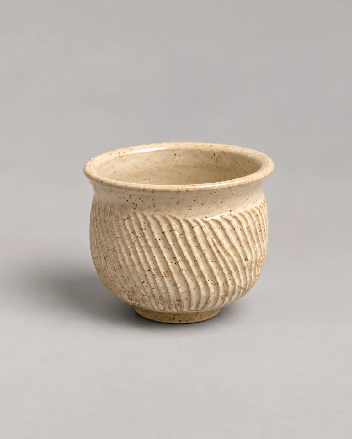 Small footed speckled cream cup with diagonal carved fluting