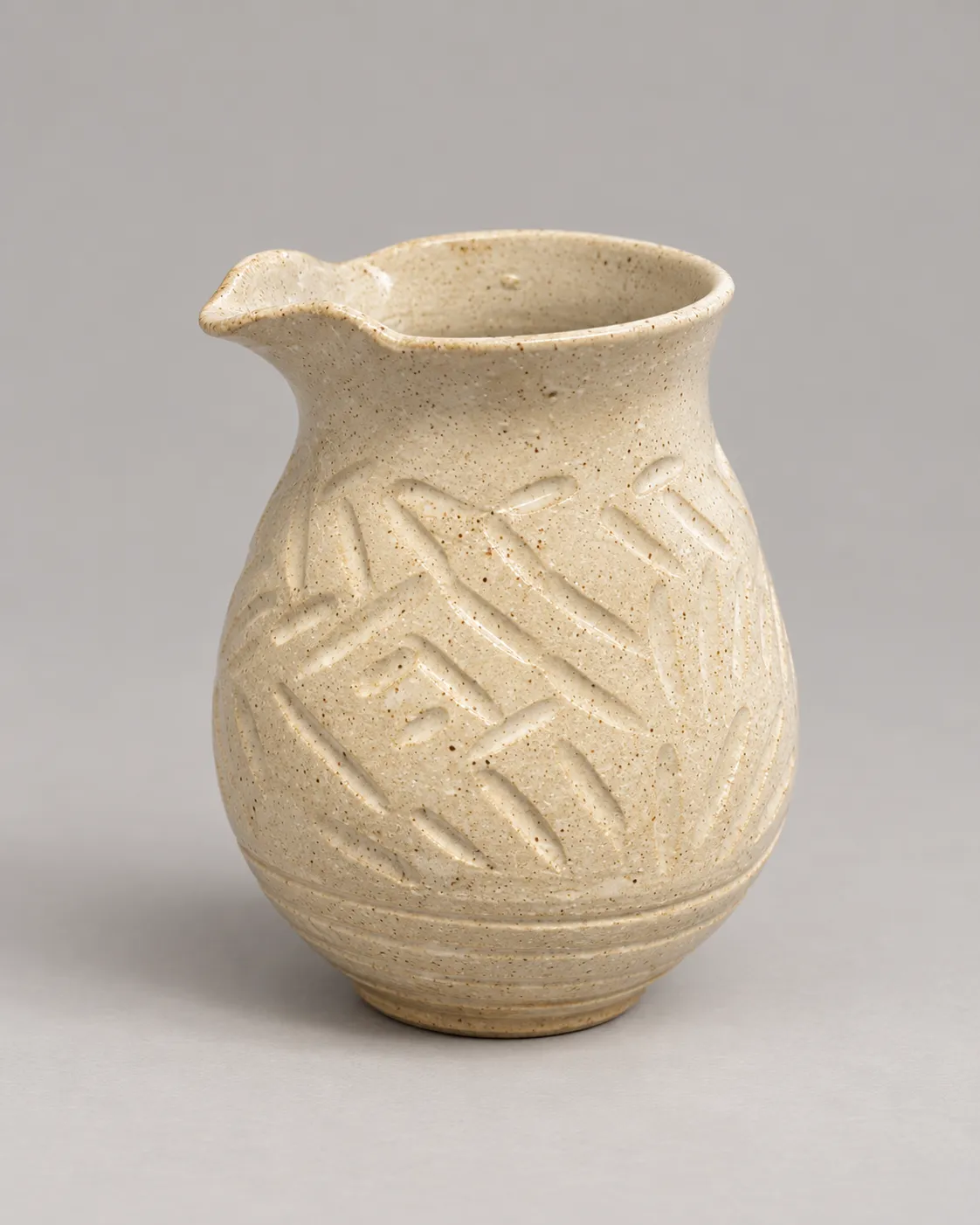 Tall speckled cream pour vase with spout, carved dashes, and ringed base