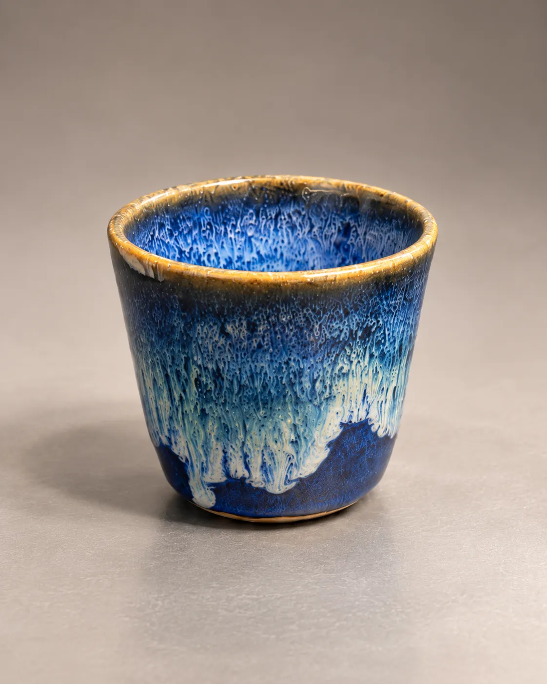 Tapered cup in bright cobalt glaze with pale blue drips and amber rim